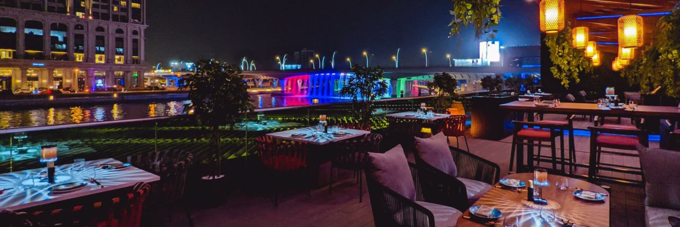 Colorfully lit dining area with view of city lights at night